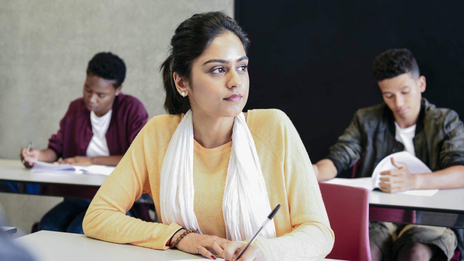 Young woman in yellow sweater doing exam, looking away
