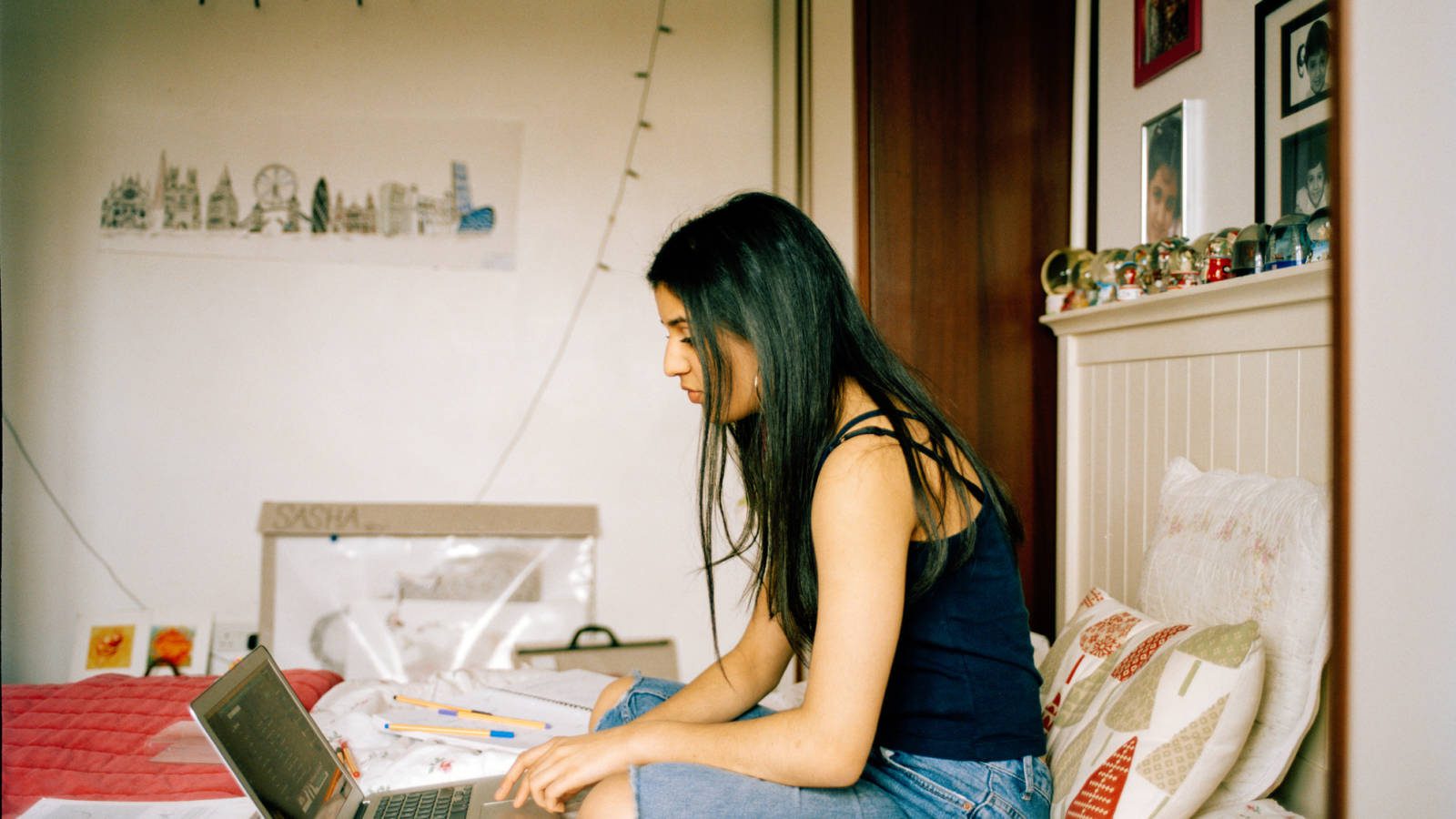 profile shot of teenage girl in her bedroom, working on laptop