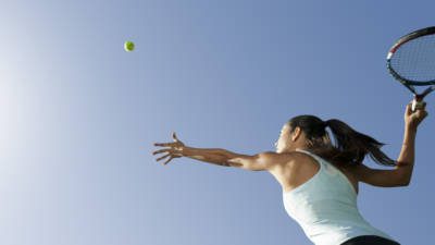 Female tennis player serving ball, low angle view