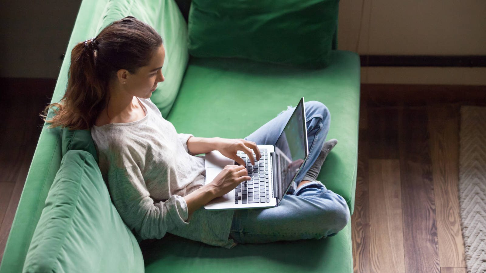 Millennial woman checking news, working online on laptop at home