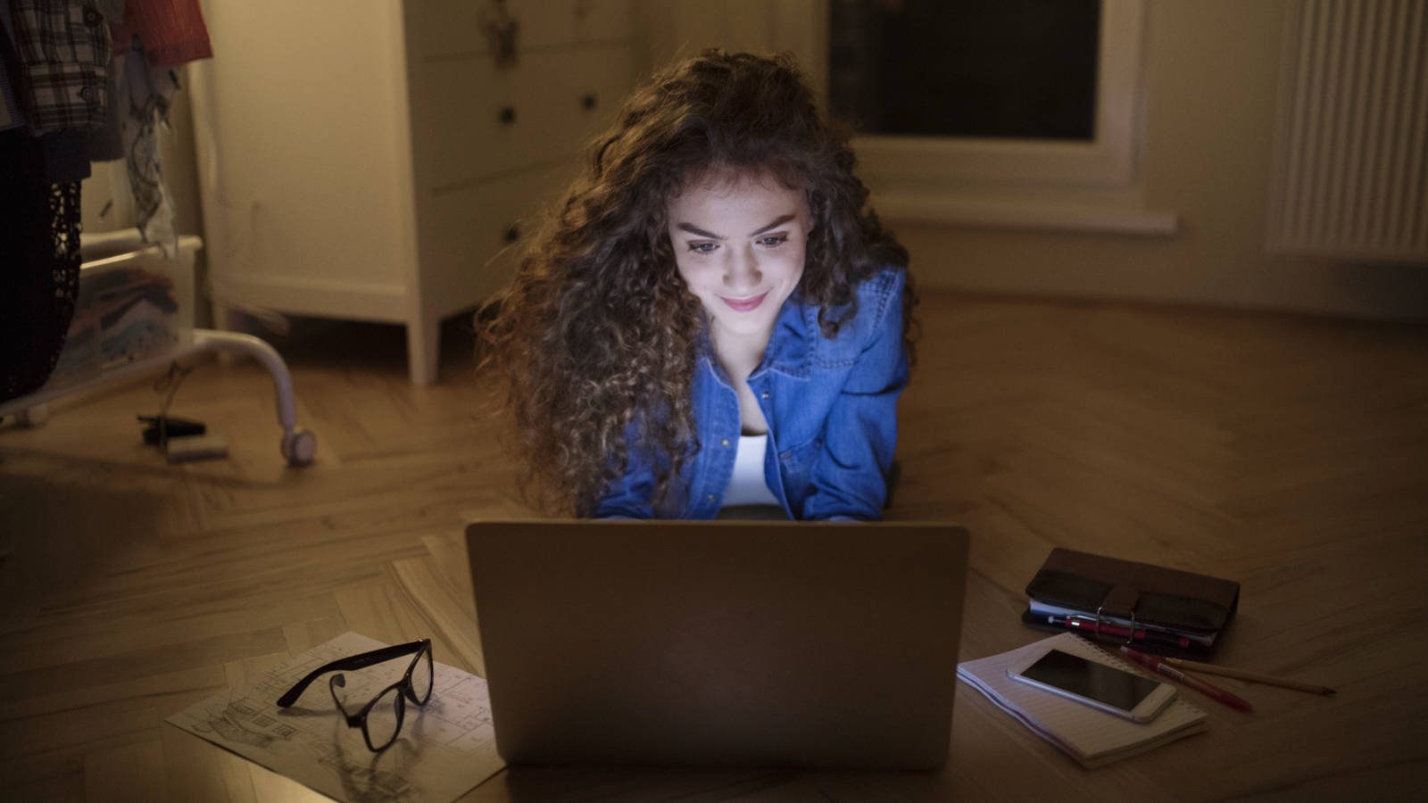 Smiling student on computer in bedroom researching how to save graduation money