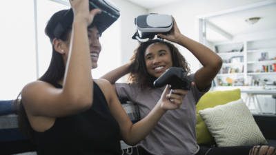 Two students playing video games wearing VR headsets and using controllers
