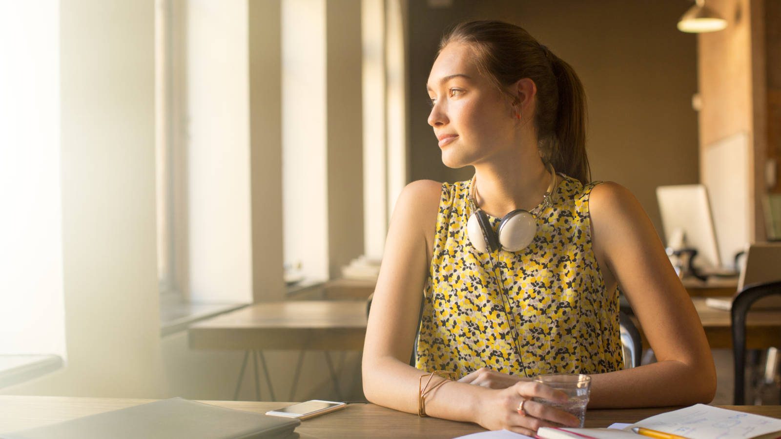 Pensive casual businesswoman with headphones looking away in office