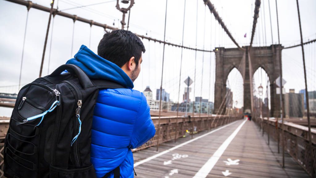 Young man walking through Brooklyn Bridge, NYC