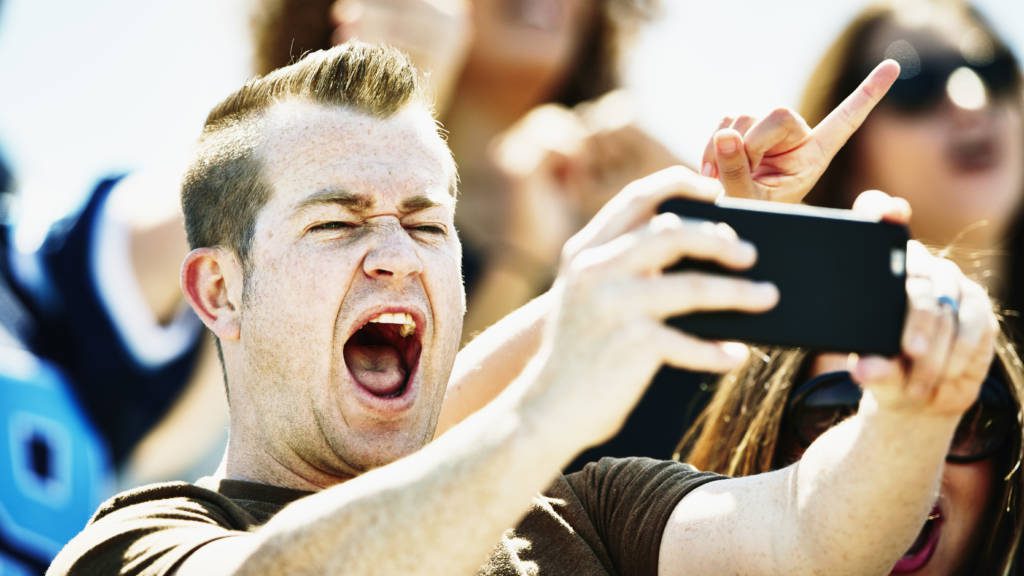 Man celebrating at football game taking selfie