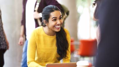 Smiling female college students with coffee and laptop