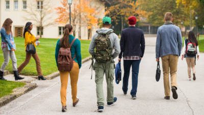 Rear View Of Students Walking Through The Park