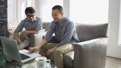 Father and son using laptop in living room