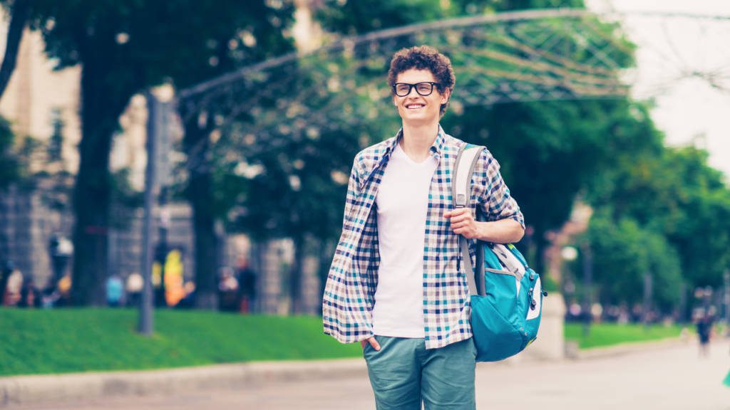 Student smiling and walking on a college campus