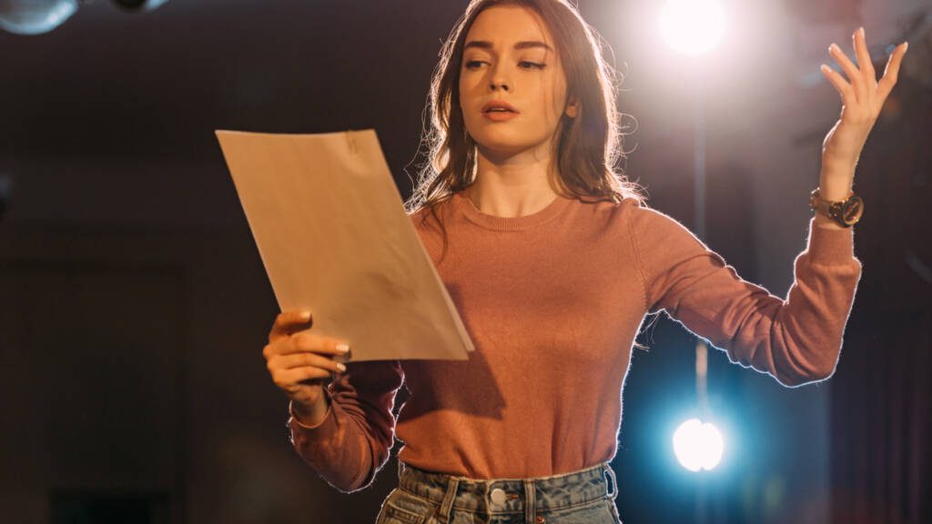 young actress reading scenario on stage in theatre