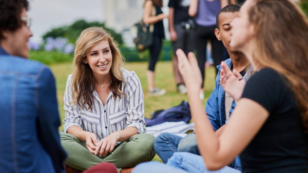 Students sitting outside on the grass in a circle during college orientation