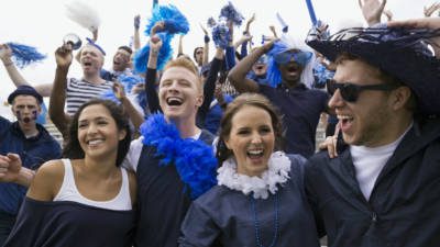 Enthusiastic fans in blue cheering bleachers sports event