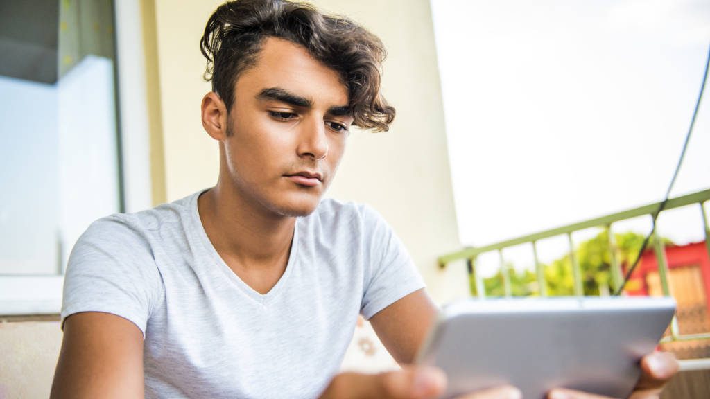 Portrait of teenage boy using digital tablet at home