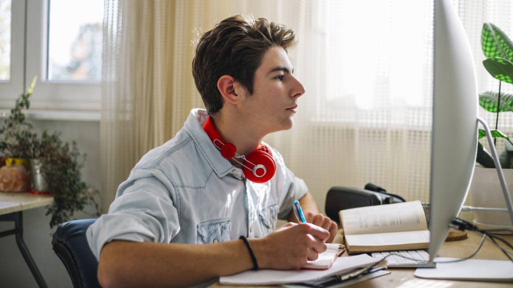 Teenage boy using computer and doing homework