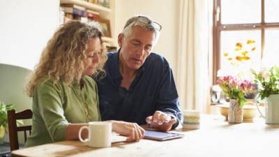 Couple sitting at table using digital tablet