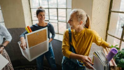 Two college students carrying boxes as they move into college housing